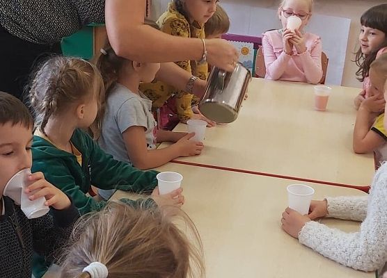 Dzieci siedzą przy stoliku i piją sok