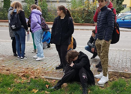 Uczniowie wykonują zadania podczas gry terenowej.