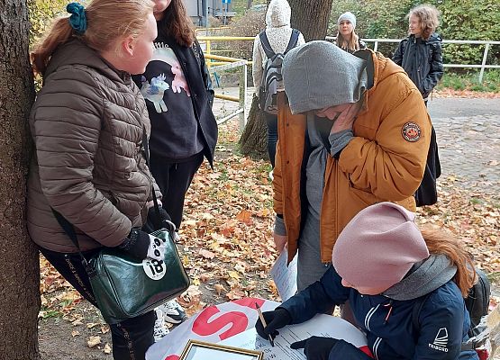 Uczniowie wykonują zadania podczas gry terenowej.