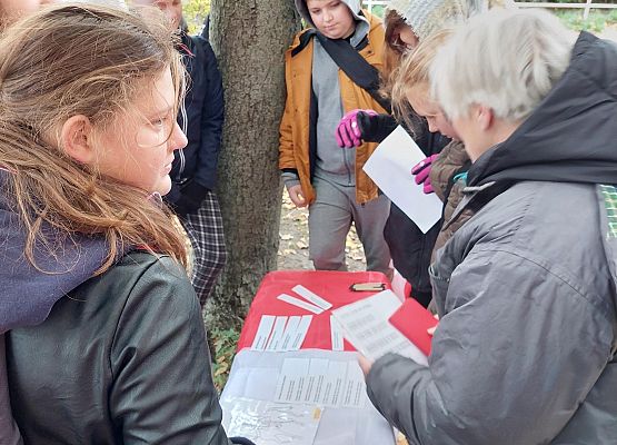 Uczniowie wykonują zadania podczas gry terenowej.