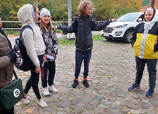 Uczniowie wykonują zadania podczas gry terenowej.