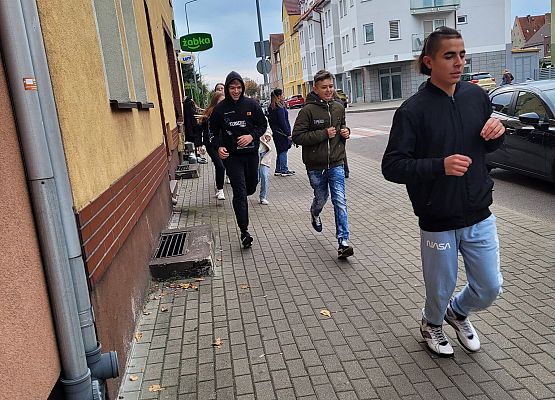 Uczniowie wykonują zadania podczas gry terenowej.