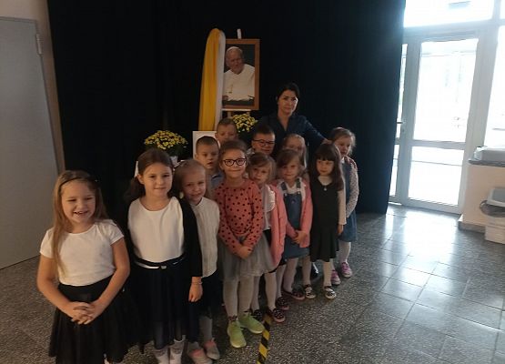 Nauczycielka z dziećmi przy portrecie Jana Pawła II