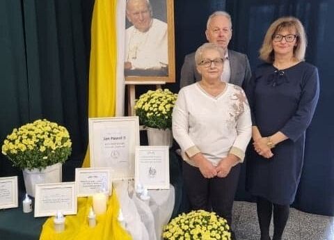 Obok portretu Jana Pawła II stoją: dyrektor, wicedyrektor i katechetka