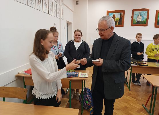 Ksiądz wręcza uczniom obrazek Jana Pawła II
