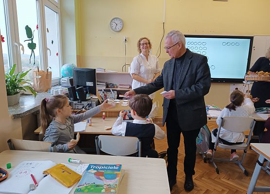 Ksiądz wręcza uczniom obrazek Jana Pawła II