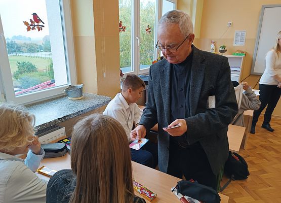 Ksiądz wręcza uczniom obrazek Jana Pawła II