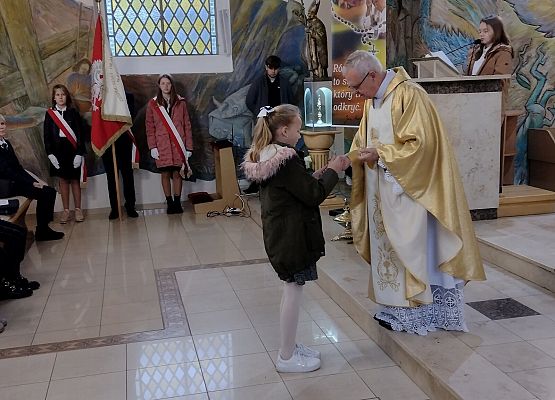 Uczennica wręcza dary księdzu