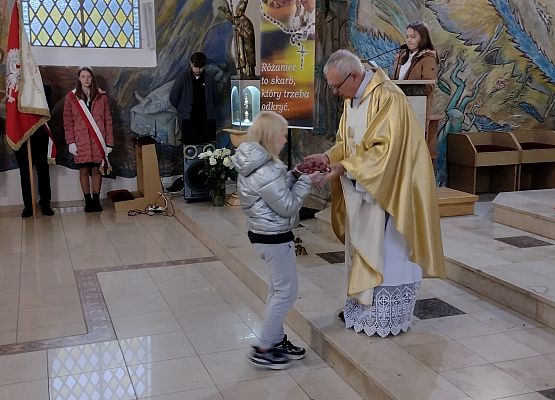 Uczennica wręcza dary księdzu