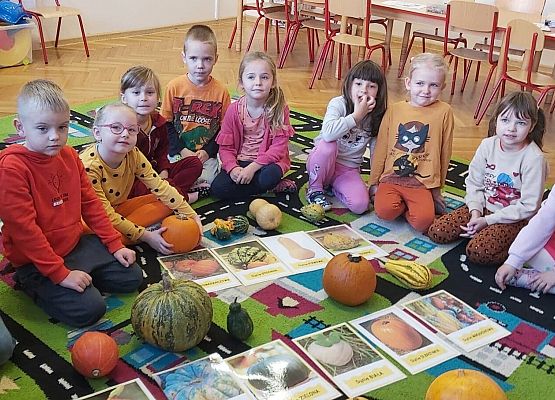 Dzieci siedzą na dywanie i oglądają dynie