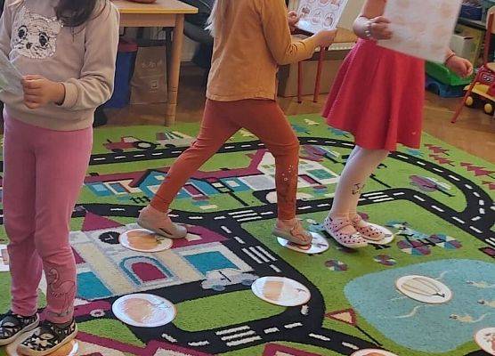 Dzieci stoją na dywanie i bawią się w kodowanie