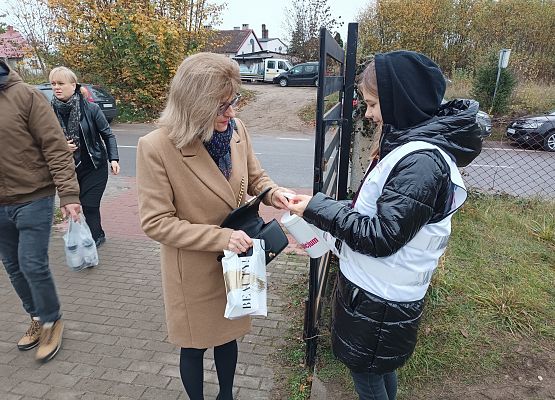 Kobieta wrzuca darowiznę do puszki
