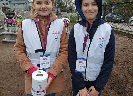 Wolontariusze stoją i trzymają puszki