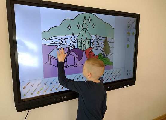 Chłopiec pracuje na monitorze interaktywnym