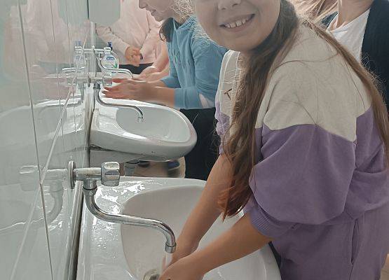 Uczennica wykonuje eksperyment z wodą, mydłem i pieprzem