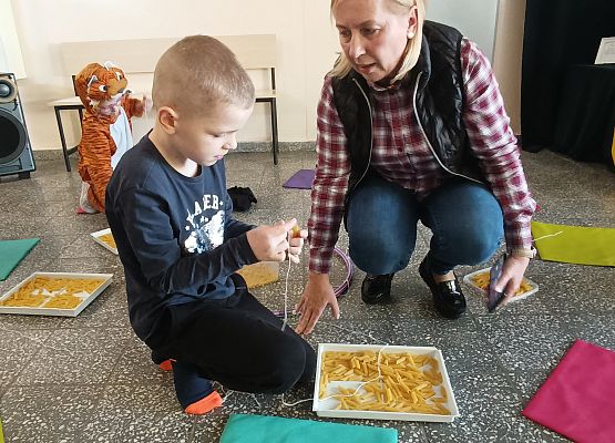 Uczeń nawleka makaron na sznurek
