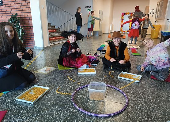 Dzieci nawlekają makaron na sznurek