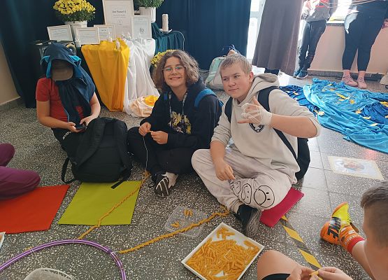 Uczniowie nawlekają makaron na sznurki