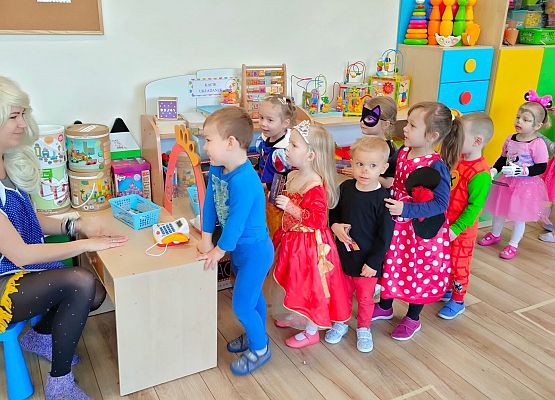 Dzieci przebrana za postacie z bajek stoją przed biurkiem