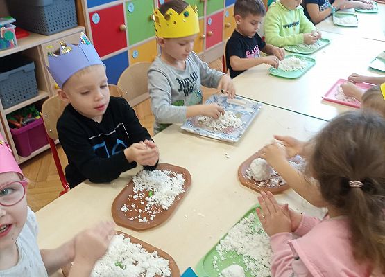 Dzieci w koronach na głowie bawią się masą plastyczną