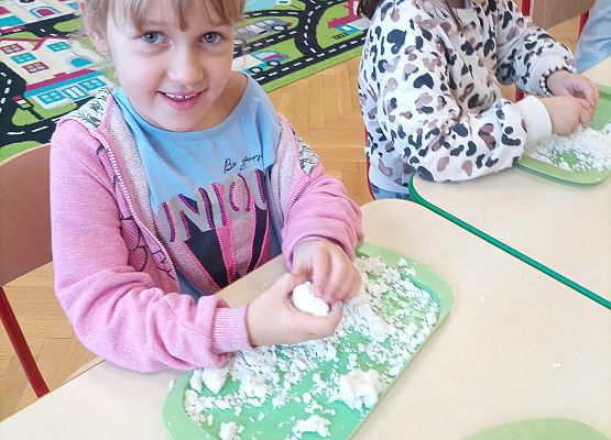 Dzieci w koronach na głowie bawią się masą plastyczną