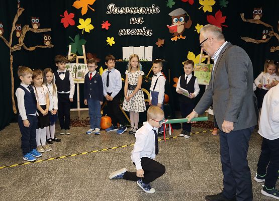 Dyrektor pasuje chłopca na ucznia