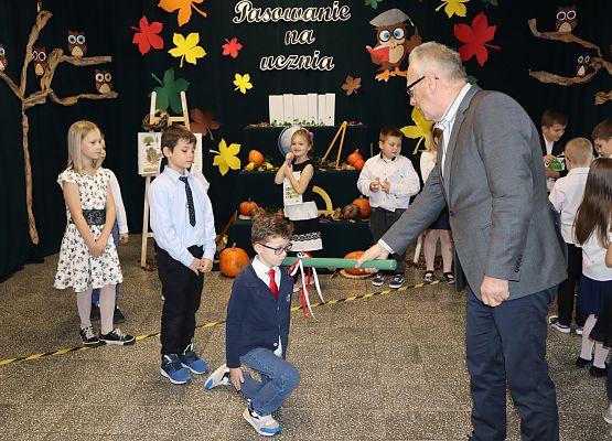 Dyrektor pasuje chłopca na ucznia