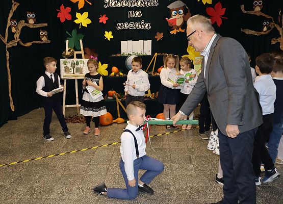 Dyrektor pasuje chłopca na ucznia