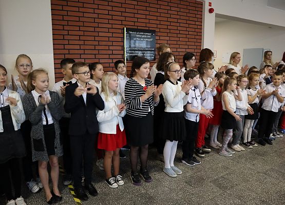 Uczniowie śpiewają hymn w szkolnym holu