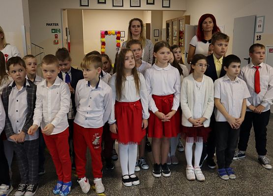 Uczniowie śpiewają hymn w szkolnym holu