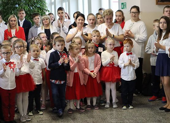 Uczniowie śpiewają hymn w szkolnym holu