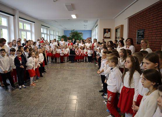 Uczniowie śpiewają hymn w szkolnym holu