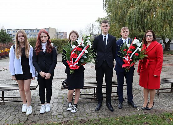 Uczniowie i nauczycielka przed złożeniem kwiatów przy Dębach Pamięci