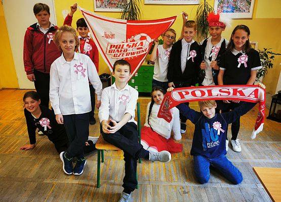 Uczniowie prezentują szalik z napisem Polska i chustę