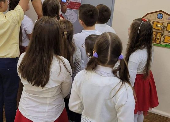 Nauczycielka odczytuje telefonem kod, obok stoją uczniowie