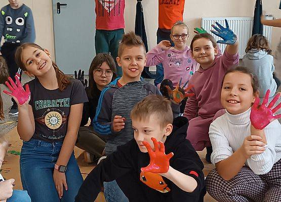 Uczniowie odciskają ślady dłoni na papierze