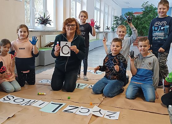 Nauczycielka z uczniami układają hasła na krzyżówce