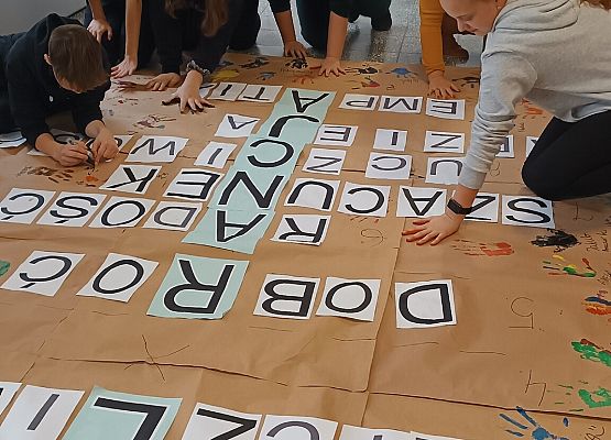Uczniowie naklejają litery na krzyżówce