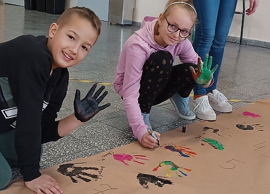 Uczniowie odciskają ślady dłoni na papierze