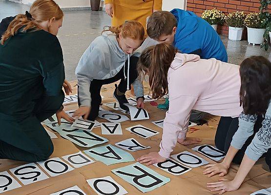 Uczniowie naklejają litery na krzyżówce