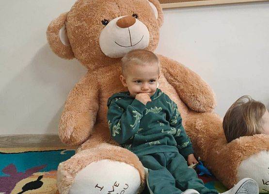 Chłopiec siedzi przy pluszowym misiu