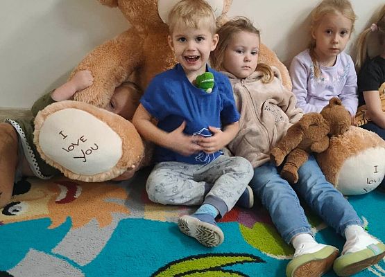 dzieci siedzą z pluszowym misiem