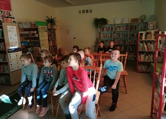 Uczniowie siedzą  i oglądają prezentację multimedialną
