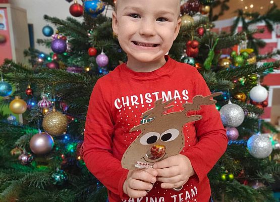 chłopiec stoi przy choince