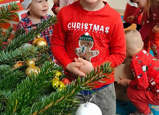 chłopiec stoi przy choince