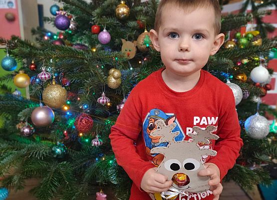 chłopiec stoi przy choince