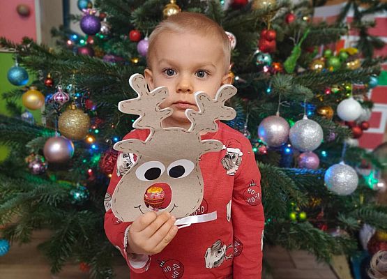 chłopiec stoi przy choince