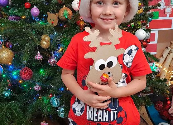 chłopiec stoi przy choince