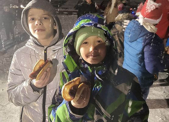 Dwaj chłopcy trzymają w dłoniach bułki z kiełbaskami