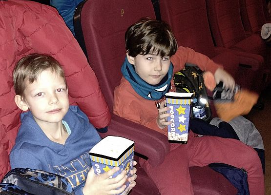 uczniowie siedzą na fotelach w kinie